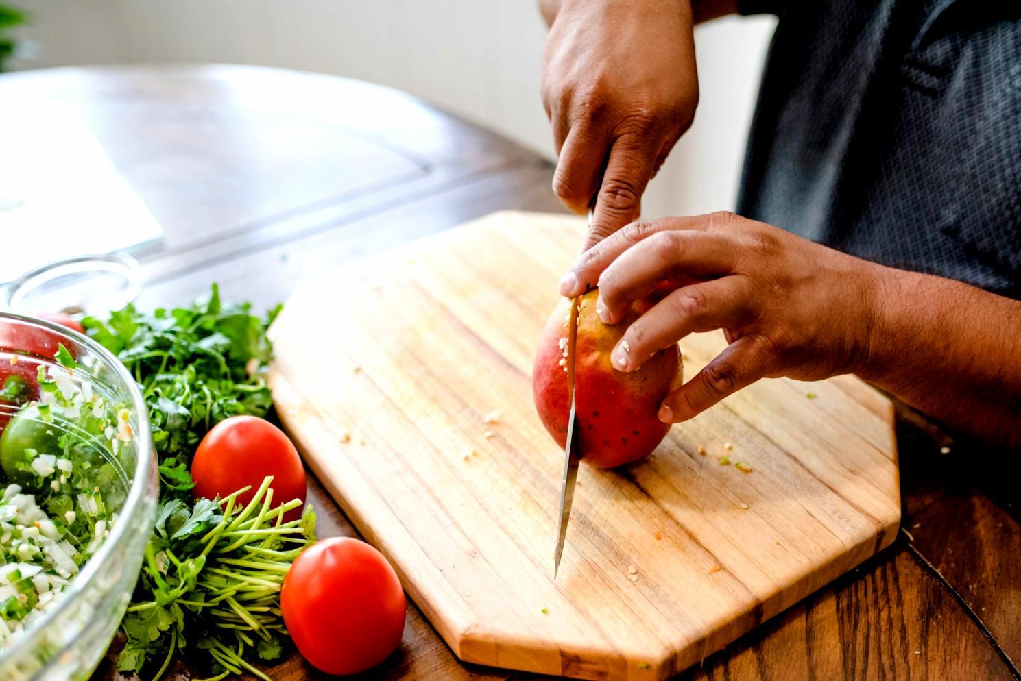 Home cook preparing ingredients with fresh herbs and vegetables spread across a kitchen counter